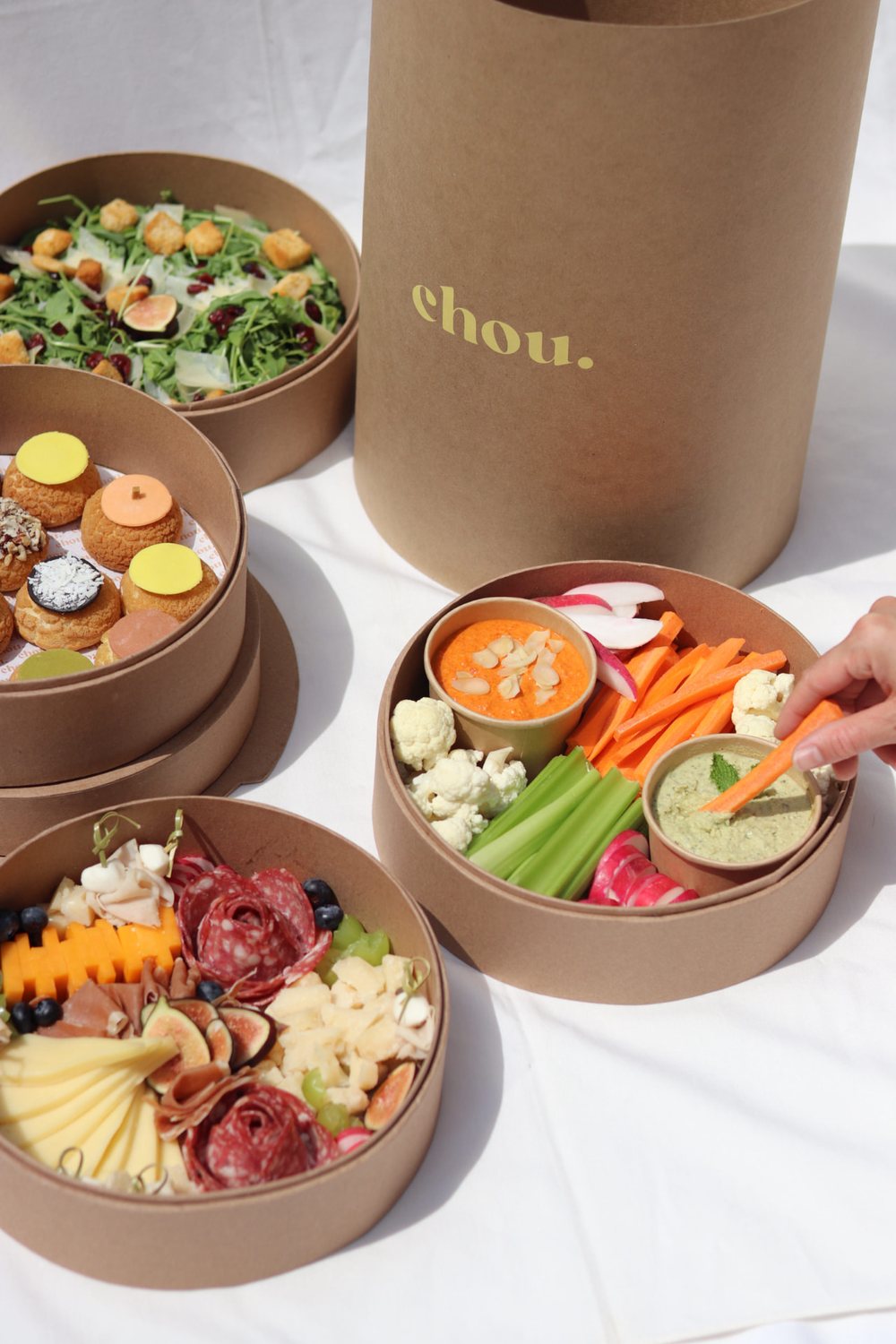 Cajas de catering de chou. junto a su caja cilíndrica con el logotipo